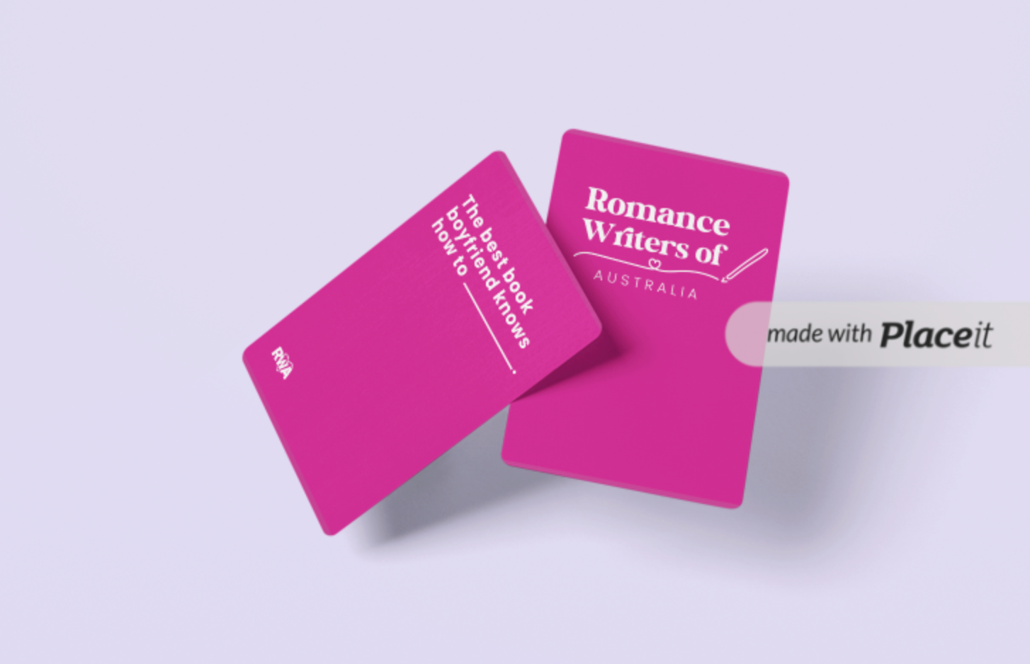 A digital mockup of two pink game cards featuring Romance Writers of Australia branding. One card displays the organisation's logo, while the other has a fill-in-the-blank prompt that reads, "The best book boyfriend knows how to _______." The RWA initials are printed on the bottom corner of the prompt card. The background is a soft pastel purple, and the cards are positioned at an angle. A watermark indicating the image was created using Placeit is visible on the right side. 